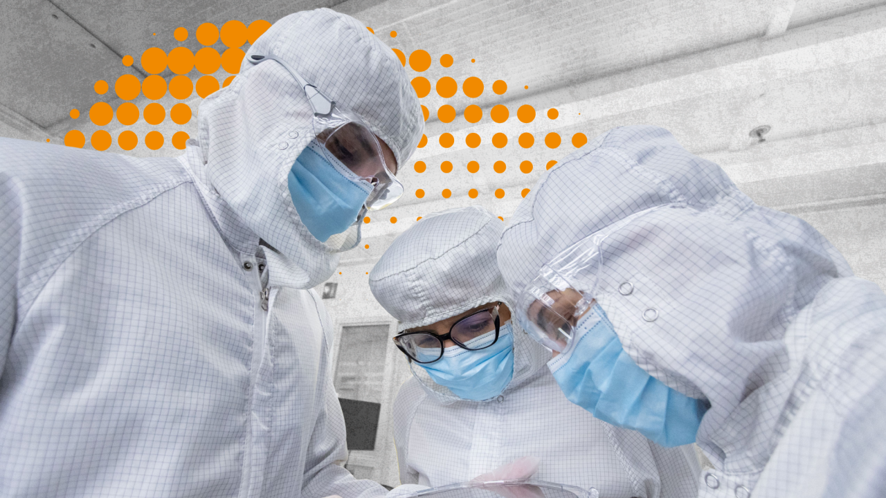 Scientists dressed up in bunny suits inspect a wafer